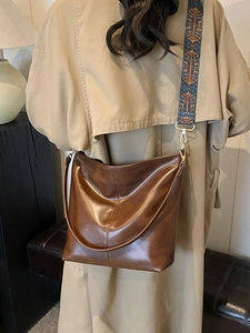 Vintage brown leather bucket bag with bohemian wide embroidered strap on a model