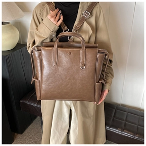 Close-up of brown PU leather backpack with contrast stitching and metal ring detail