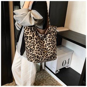 Close-up of leopard print oversized tote bag with metal logo detail on the shoulder