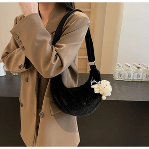 Detail of black plush crescent bag with soft faux fur texture and white cartoon pendant