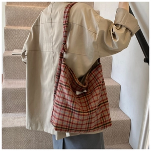 Détail du sac cabas à carreaux rouge et marron montrant le tweed et l'étiquette tissée