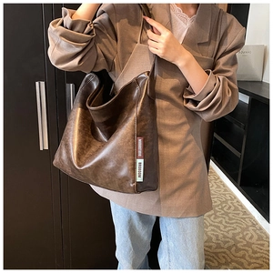 Detail view of vintage brown PU leather shoulder bag with unique fabric logo patches