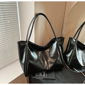 Sac fourre-tout en cuir noir brillant avec longues anses se reflétant dans un miroir