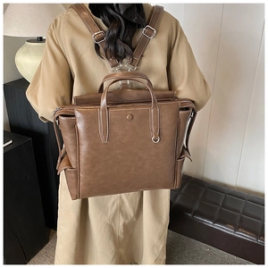 Detail view of vintage brown leather backpack showing contrasting white stitching and strap