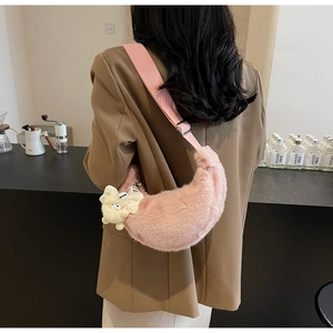 Detail of pink plush crescent crossbody bag with cute monster charm and wide strap