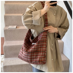 Détail de la texture en laine à carreaux épais et de l'étiquette tissée blanche du sac
