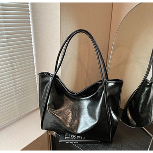 Détail d'un sac cabas noir brillant montrant la texture lisse et les longues bandoulières