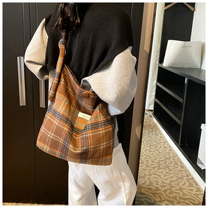 Détail du sac cabas à carreaux orange et marron avec bouton latéral et étiquette tissée