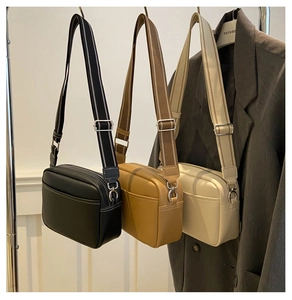 Detail view of stylish crossbody camera bags with wide striped straps in three solid colors