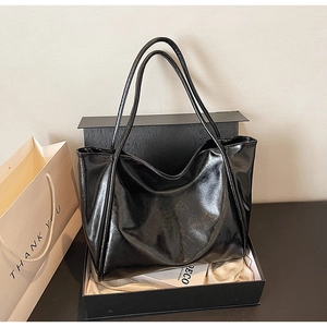 Vue détaillée du sac cabas en cuir noir brillant présenté dans un coffret cadeau élégant