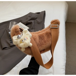 Detail of plush brown crescent shoulder bag with canvas strap and cute cartoon charm