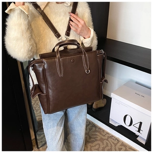 Detail of vintage brown leather backpack with contrast stitching on a model
