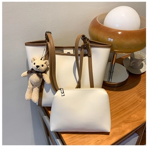 Detail of cream tote bag with contrast trim, inner pouch and woven bear charm