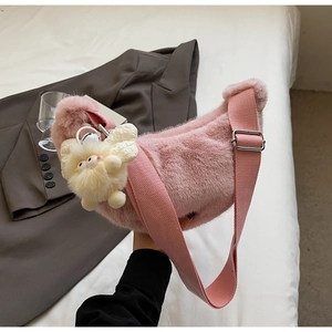 Detail of pink plush crescent bag with soft faux fur texture and cute doll charm
