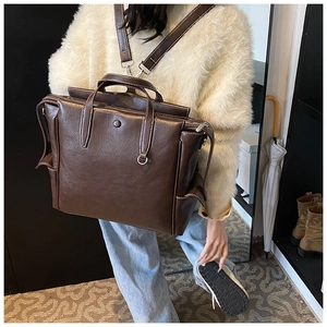 Detail of dark coffee leather backpack with white contrast stitching and metal hardware