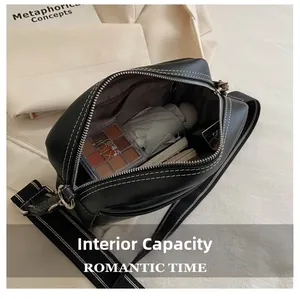 Macro detail of black leather crossbody bag interior showing large capacity and white stitching