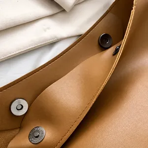 Dettaglio della chiusura magnetica e della pelle marrone martellata di una borsa