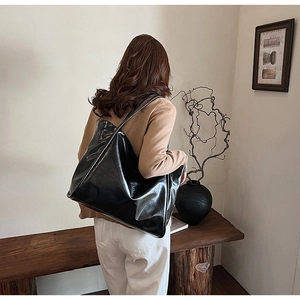 Vue lifestyle d'un grand sac cabas noir brillant en similicuir porté par un mannequin