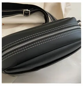 Close-up of smooth silver zipper and white contrast stitching on black leather handbag
