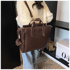 Detail of dark brown tote backpack with white contrast stitching and adjustable straps