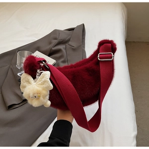 Detail of burgundy plush crescent bag with fuzzy rabbit charm and adjustable strap
