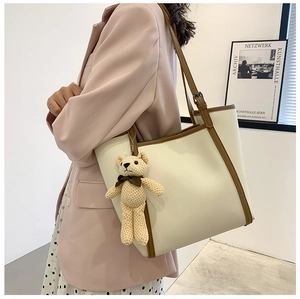 Detail of beige large capacity tote bag with brown trim and cute knit bear charm
