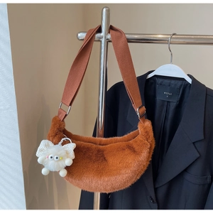 Close-up of brown plush faux fur hobo bag featuring a cute cartoon monster pendant