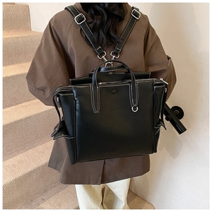 Detail of black leather backpack with white contrast stitching and silver metal buckles