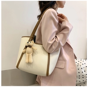 Detail of the high-capacity tote bag in cream with dark brown trim and bear charm