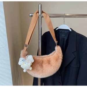 Detail view of plush crescent shoulder bag with soft faux fur and cute monster charm
