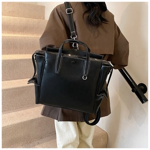 Detail of a black large tote backpack with contrast white stitching and side pocket