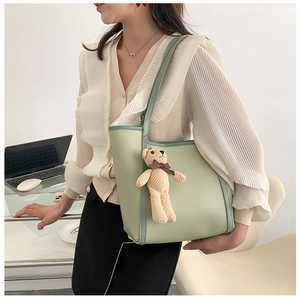 Detail of mint green tote bag with dark green trim and a cute plush bear pendant