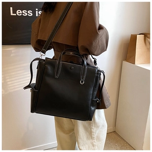Detail view of black leather tote bag with white contrast stitching and side pocket