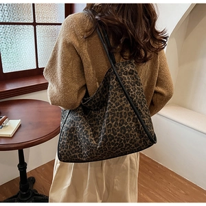 Grand sac cabas léopard porté à l'épaule dans un café rétro à l'ambiance chaleureuse