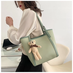 City lifestyle shot of a large light green tote bag with contrast trim and bear charm