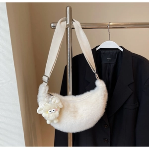 Detail of white plush crescent bag with fuzzy sheep charm and wide adjustable strap