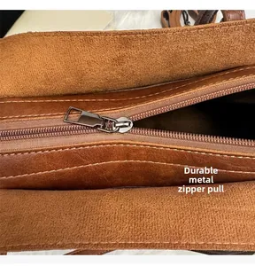 Detail shot of the sturdy silver zipper and leather stitching on the brown tote bag
