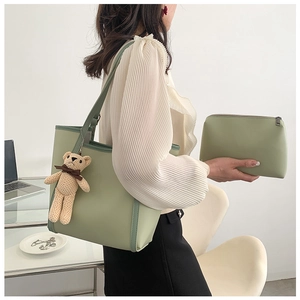 Detail view of sage green tote bag with contrast piping and a cute bear charm accessory