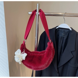 Detail of burgundy plush crescent bag with wide strap and cute white bear charm