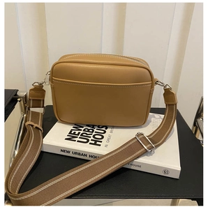 Detail of camel crossbody bag with white stitching and adjustable canvas shoulder strap