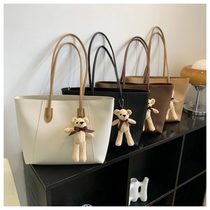 Detail showing four classic colors of minimalist tote bags with cute knit bear charms