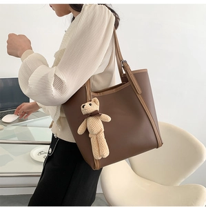 Detail view of brown large capacity tote bag with texture and plush bear accessory