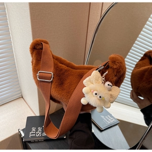 Brown plush crescent shoulder bag with wide strap and cute monster charm detail