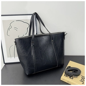 Detail view of black faux leather tote bag with fine wrinkled texture and gold zipper