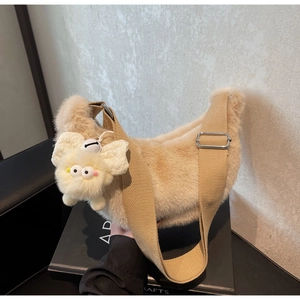 Detail of plush crossbody bag with furry texture, canvas strap and cartoon eye charm