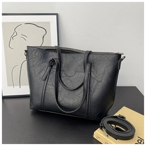 Detail shot of black textured tote bag featuring double handles and detachable shoulder strap