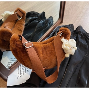 Detail of soft brown plush crescent bag with wide strap and white rabbit charm accessory