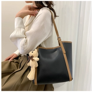 Detailed side view of high-quality contrast-color tote bag with decorative bear pendant