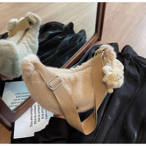 Detail of plush beige hobo bag with adjustable strap and cute bow keychain accessory