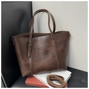 Brown vintage tote bag with pleated texture and adjustable strap on art books